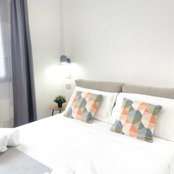 Interno camera da letto moderna dell'appartamento Domus Luna, casa vacanze a Teulada con letto matrimoniale e arredi chiari