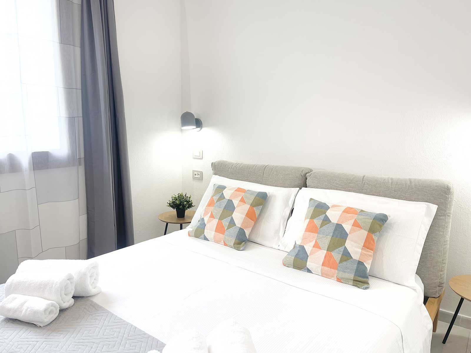 Interno camera da letto moderna dell'appartamento Domus Luna, casa vacanze a Teulada con letto matrimoniale e arredi chiari