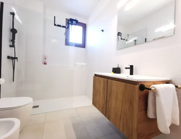 Dettaglio del lavabo da appoggio su mobile in legno moderno nel bagno di Domus Luna, completo di ampio specchio e rubinetteria nera di design.