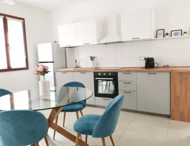 Angolo cottura di Domus Luna con piano induzione, lavello moderno, pensili bianchi e paraschizzi in legno coordinato, perfettamente attrezzato per cucinare.