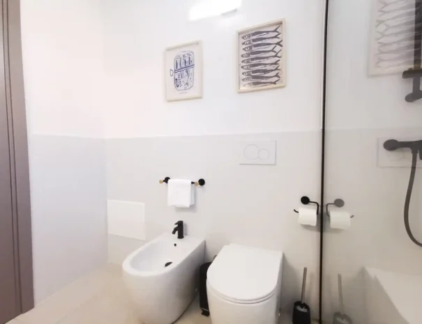 Dettaglio dei sanitari sospesi e dei rivestimenti moderni nel bagno di Domus Luna, evidenziando la massima pulizia e la cura dei dettagli per gli ospiti.