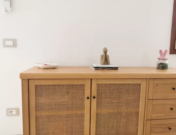 Dettaglio di una credenza in legno naturale in stile moderno nell'area living di Domus Luna, con rifiniture eleganti e decorazioni minimaliste.