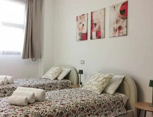 Seconda camera da letto di Domus Luna arredata con due letti singoli affiancati, comodino centrale e quadri moderni, ideale per bambini o viaggiatori singoli.