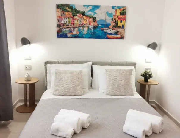 Ampia camera da letto padronale di Domus Luna con letto matrimoniale, testiera in legno naturale, illuminazione di design e atmosfera rilassante per gli ospiti.