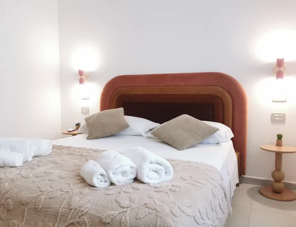 Dettaglio del letto matrimoniale con testata moderna e illuminazione a Teulada.